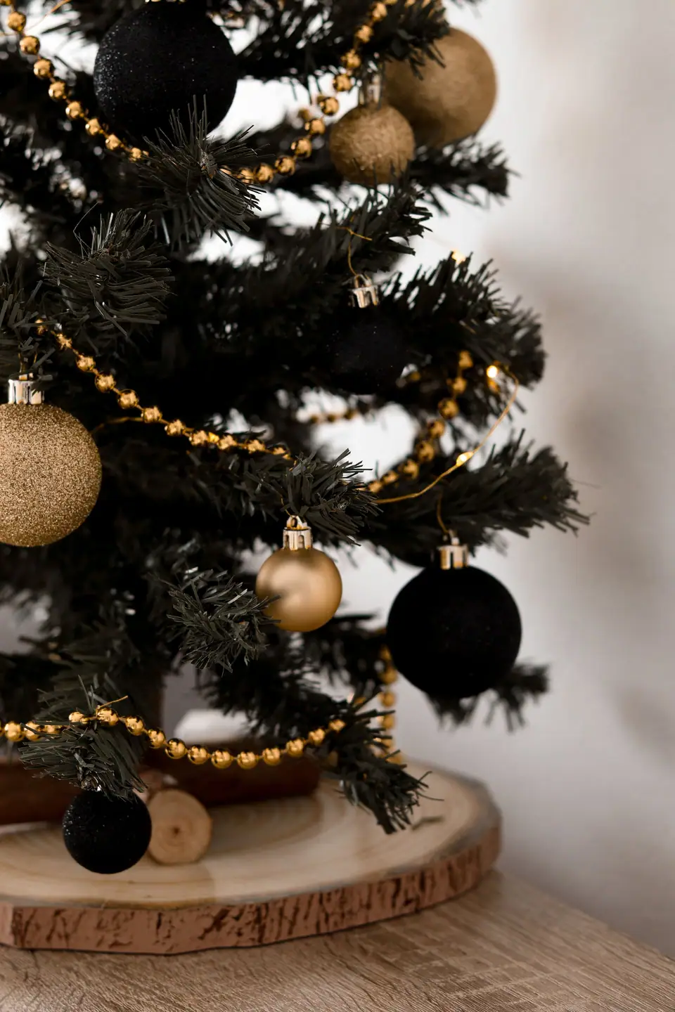 A Christmas tree hung with black and gold ornaments and small warm lights