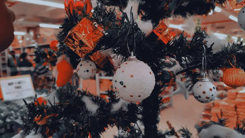 Close view of a dark Christmas tree decorated with orange and white ornaments