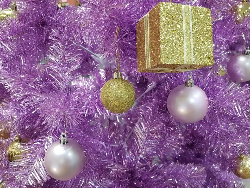 Gold and lilac baubles on a purple tinsel Christmas tree